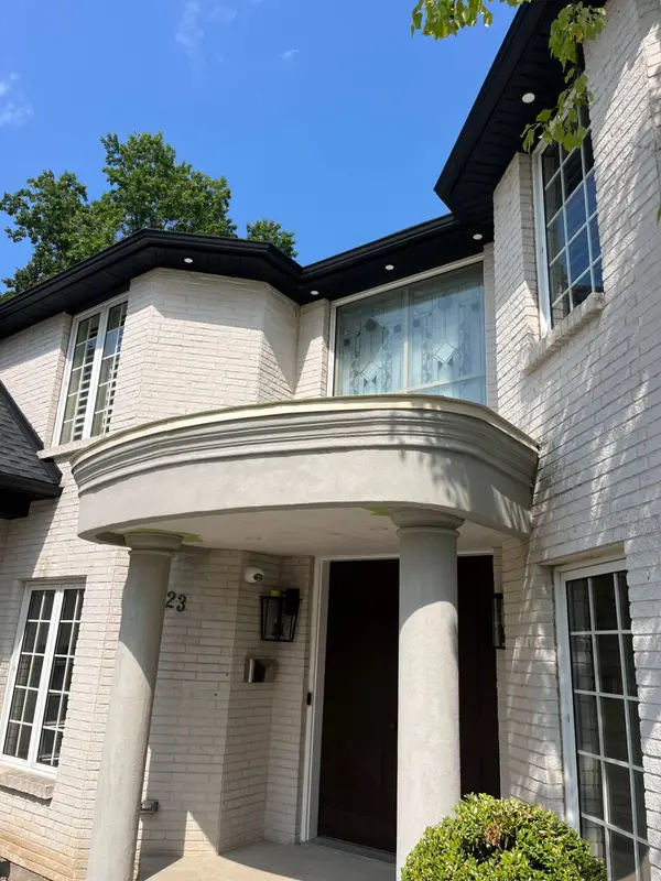 Brick home entrance with a curved portico, columns and dark metal fascia trim