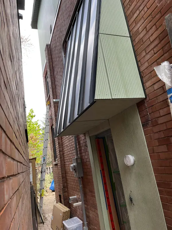 Green metal-clad bay projection on a brick house