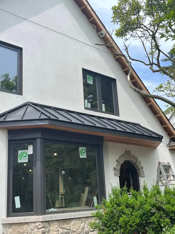 Stucco house with a new black standing-seam metal roof over the bay window