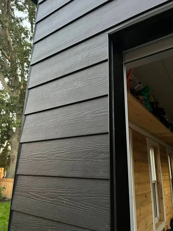 Black textured lap siding beside a window opening
