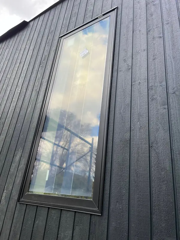 Black vertical siding around a tall window