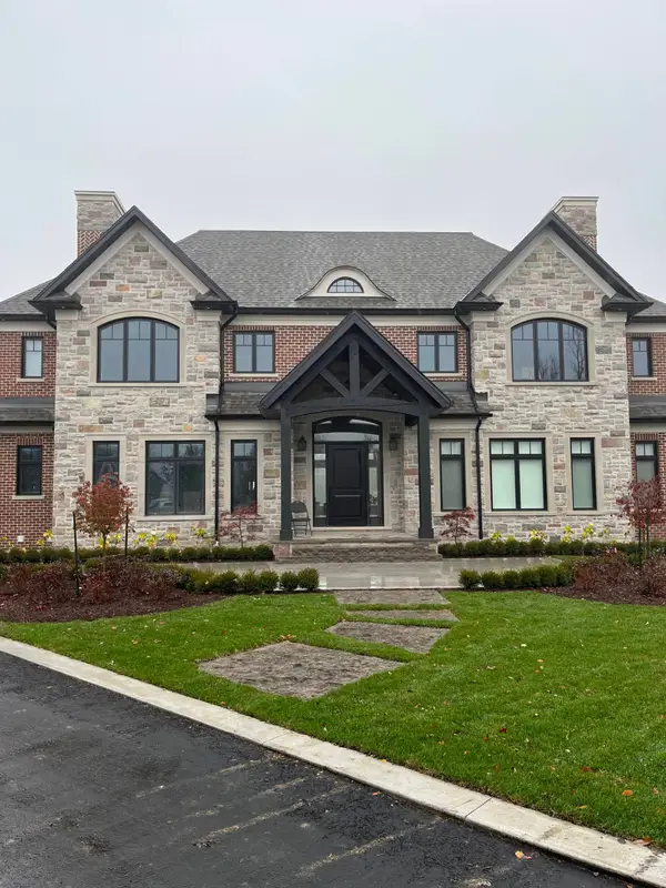 Large stone house with dark roof trim and a front lawn