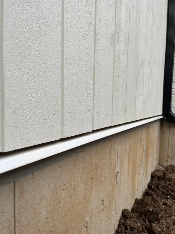 Light vertical panel siding above a concrete foundation