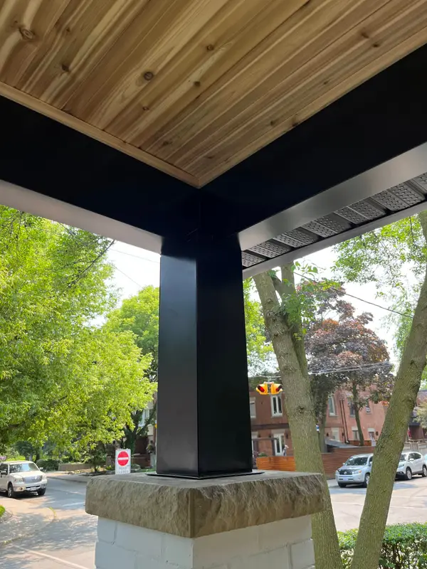 Porch post wrapped in black metal under a cedar ceiling