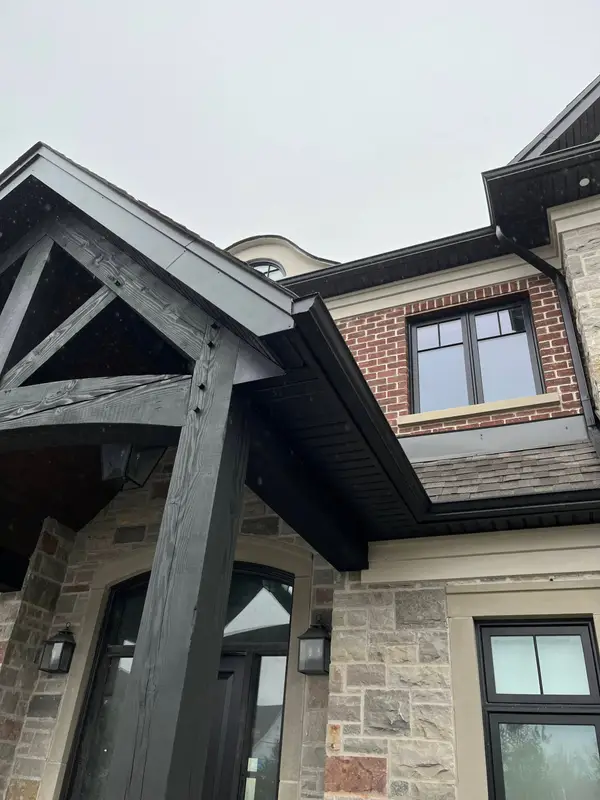 Stone and brick home with a black timber gable and fascia
