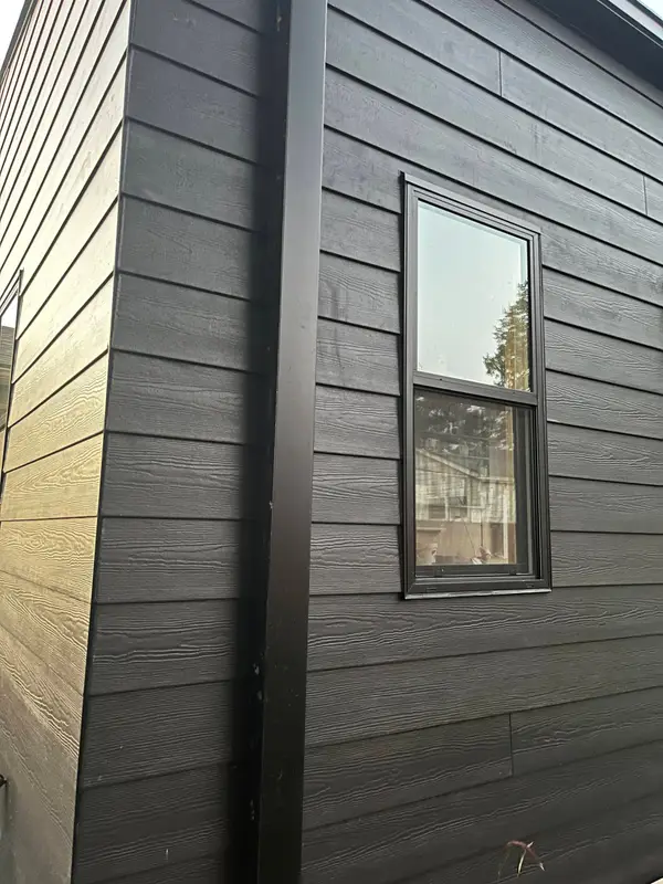 Black horizontal lap siding with corner trim and a window