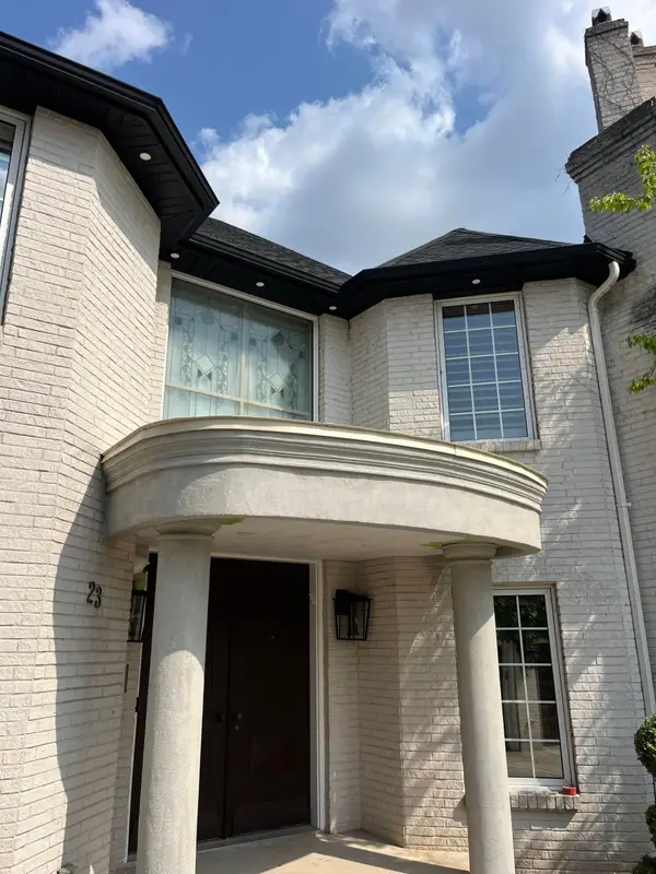 Brick home entrance with a curved portico and dark metal roof trim