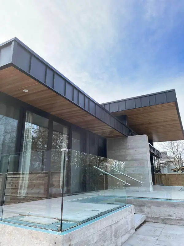 Modern house with a cantilevered wood soffit, metal fascia and glass railing