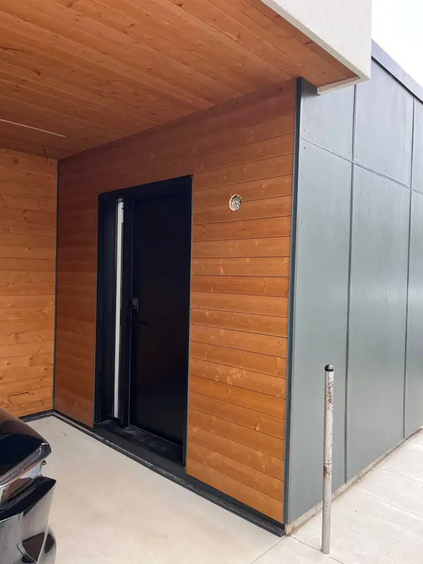 Wood-look and grey metal wall panels around a black door
