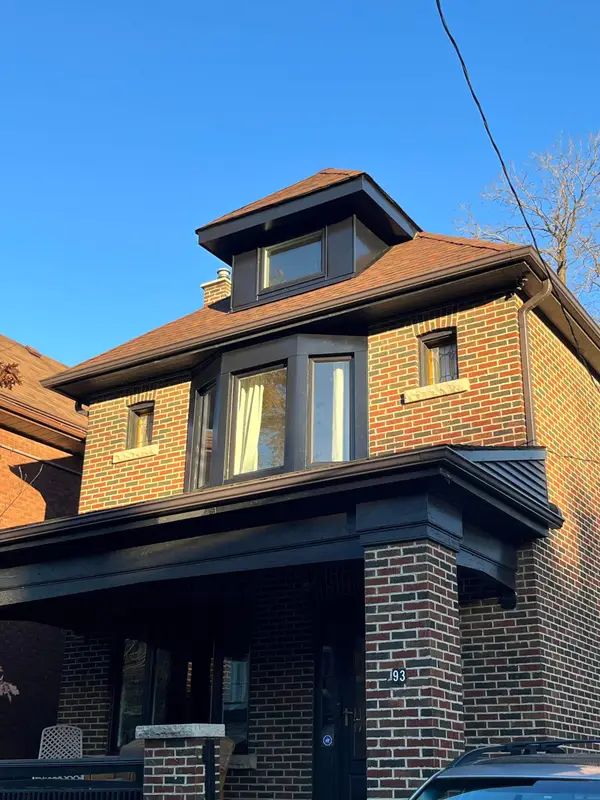 Brick home with a black metal-clad porch roof and dormer