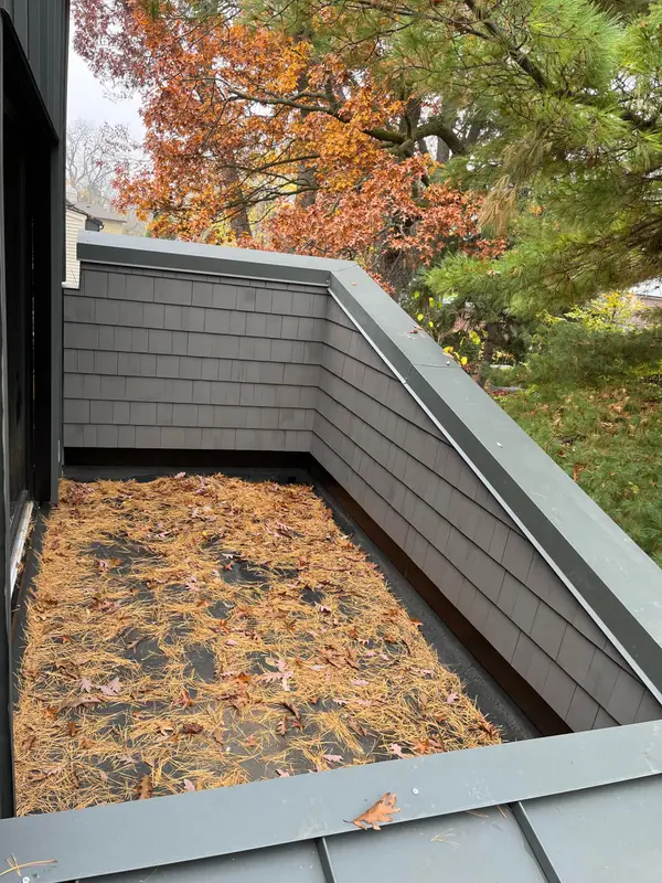 Rooftop planter enclosure with grey shingle siding and metal cap