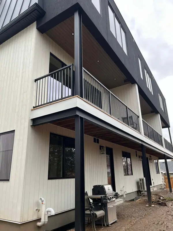 Townhouse rear with white vertical siding, black fascia and balconies